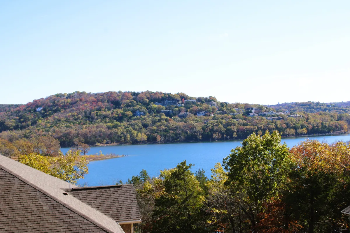 A breathtaking wide-angle view of Table Rock Lake surrounded by hills, trees, and a vibrant sky. The shoreline and expansive water create an inviting atmosphere for outdoor activities like hiking, boating, and sunset watching.