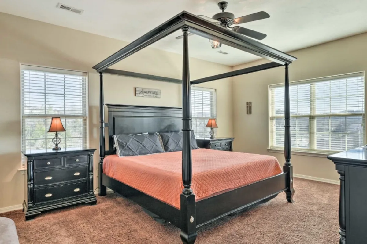 A serene bedroom featuring a four-poster king-sized bed, flanked by nightstands and with soft window light streaming in. The room feels peaceful and inviting, with cozy linens and soothing decor that emphasizes comfort and relaxation.