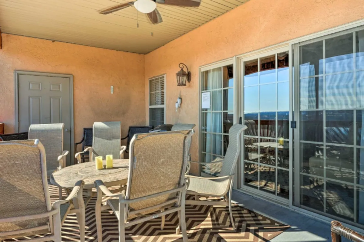 This scene looks out across a private deck through glass doors, featuring an outdoor table, comfortable seating, and a scenic view beyond. The setting communicates a relaxed space ideal for morning sunrises or sunset dinners, inviting guests to enjoy the outdoors while remaining comfortably connected to the main living area.
