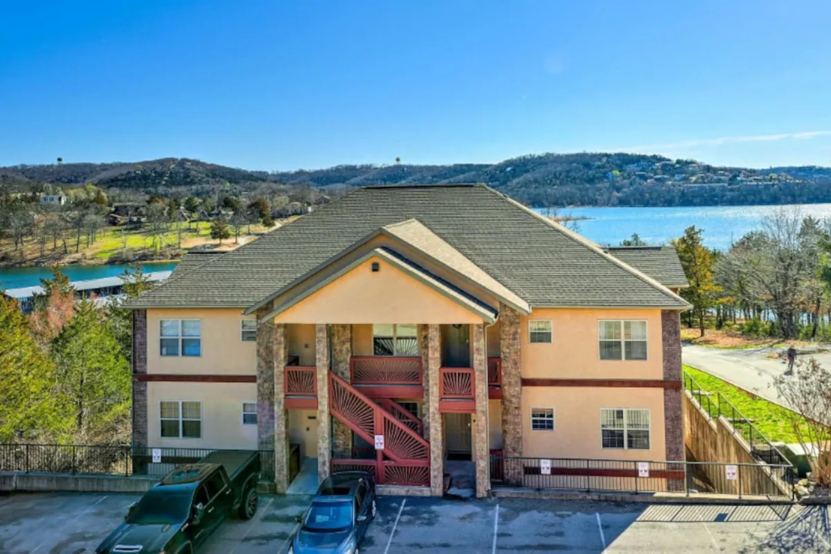 The image showcases the modern exterior of a luxury condo building with a striking red staircase, set against the tranquil backdrop of a lake at sunset. The scene captures inviting spaces for relaxation, hints of community activity, and the soothing ambience of waterfront living.