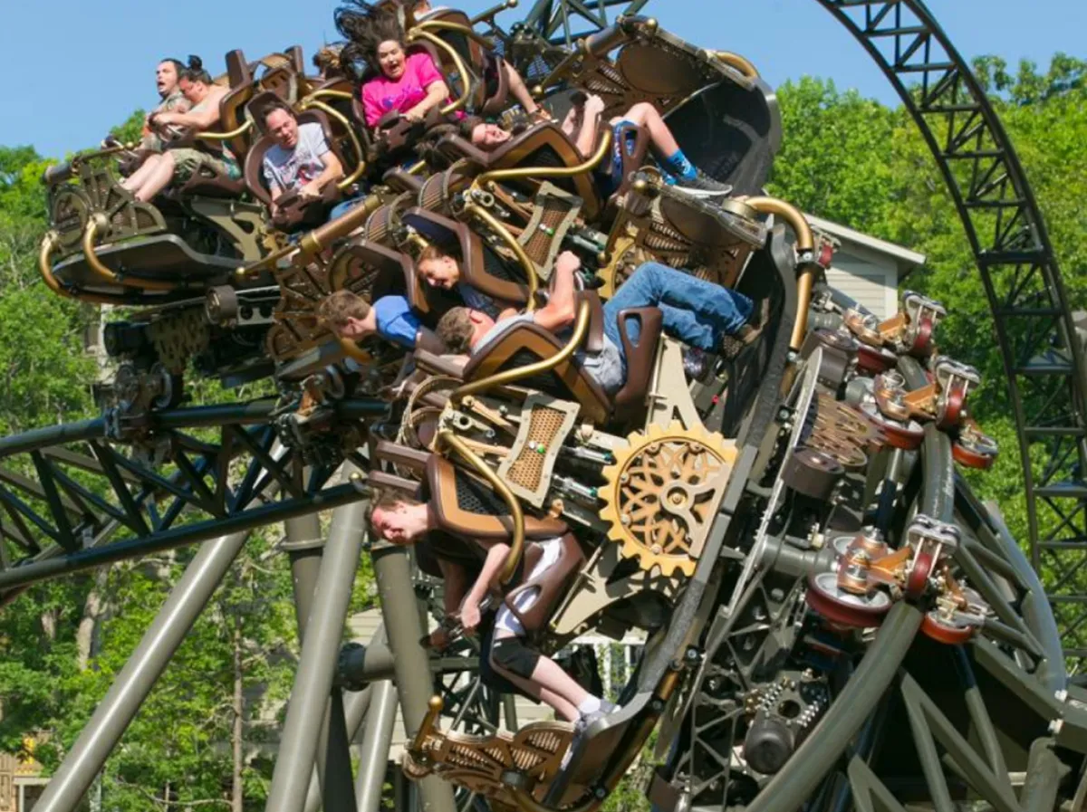 A close-up, action-filled image of a roller coaster in motion, with riders experiencing the thrill and excitement of the ride. The background hints at more amusement park attractions and a lively park setting.