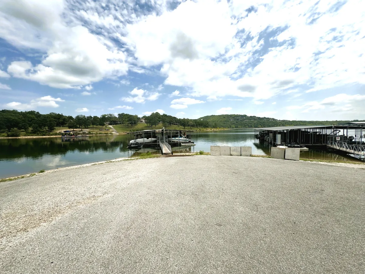 This image features a panoramic view of docks stretching into the lake, with several boats gently bobbing on the water and an expansive sky above. The inviting scene suggests both the community aspect of dockside living and the natural beauty of the lake.